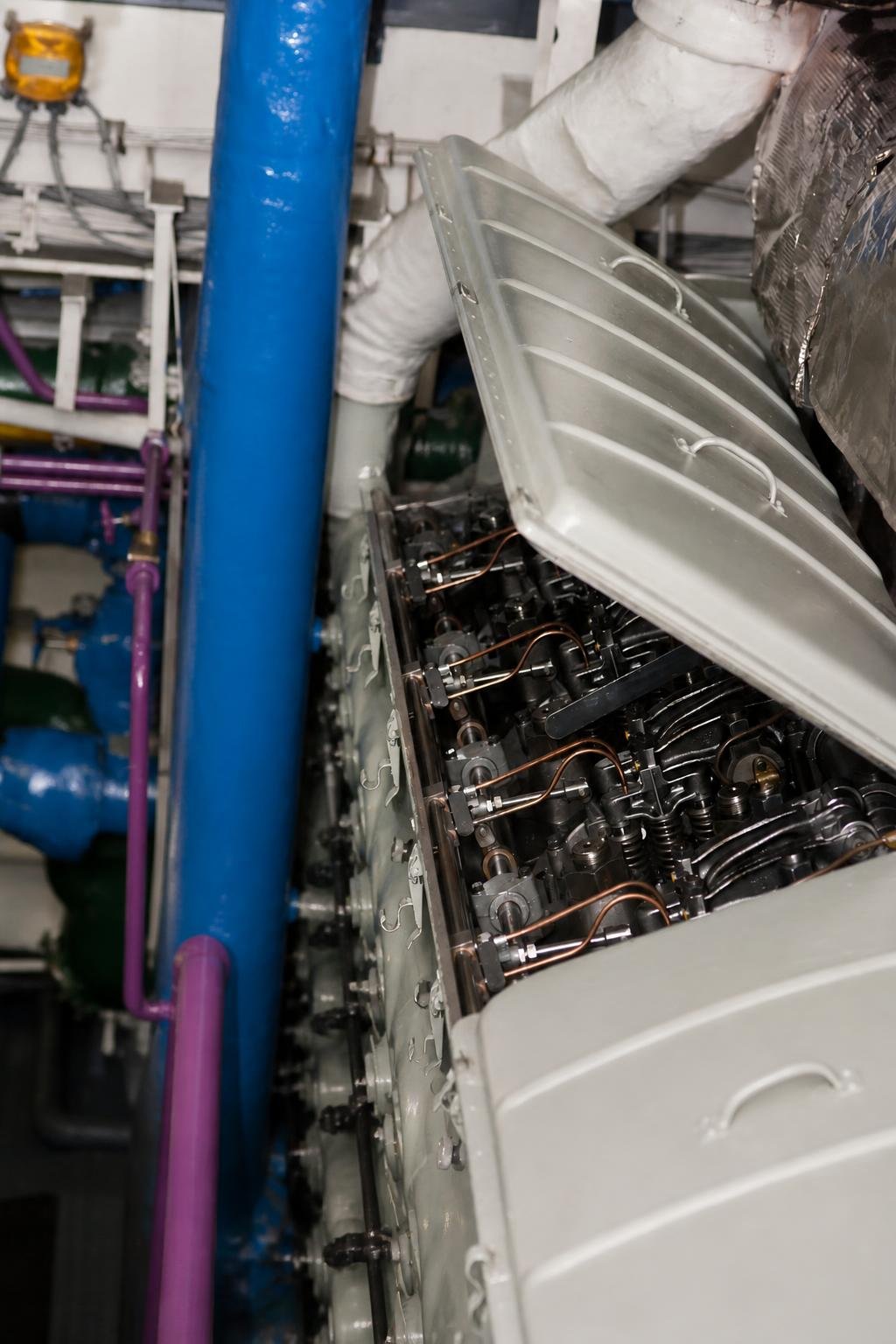 Two sailors lift the engine cover while checking a diesel emergency power generator aboard USS John C. Stennis.