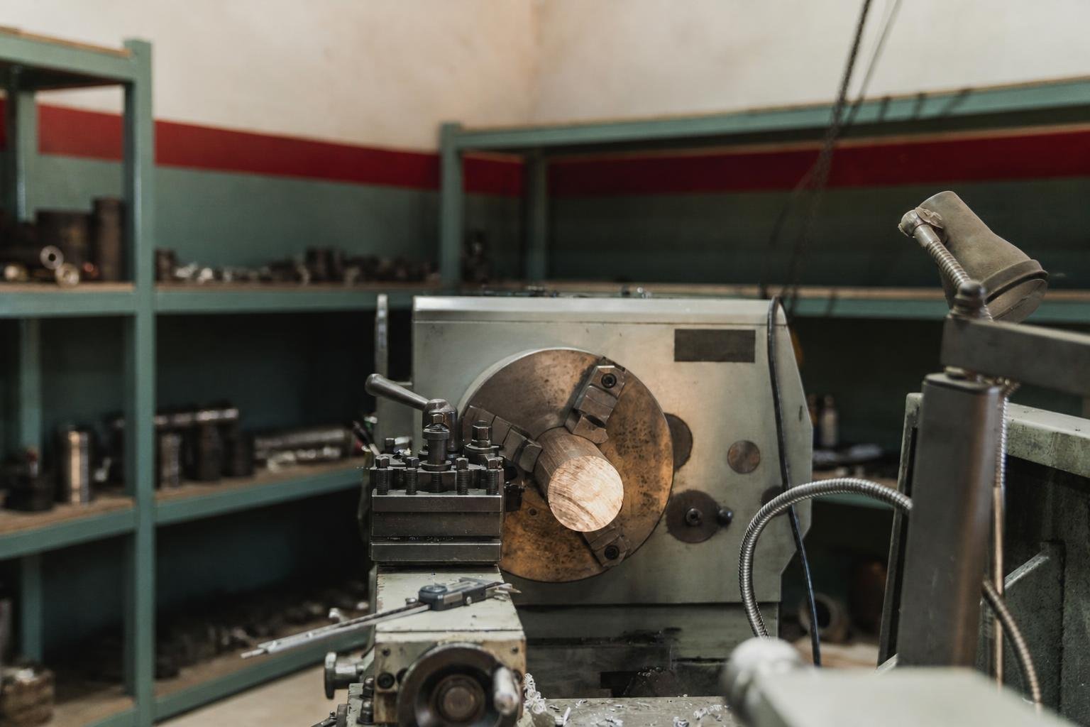 Active operator at a large manual lathe with genuine workshop depth behind him.